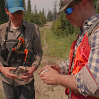 PEMC Vice President of Exploration, Thomas Hawkins with field assistant examining